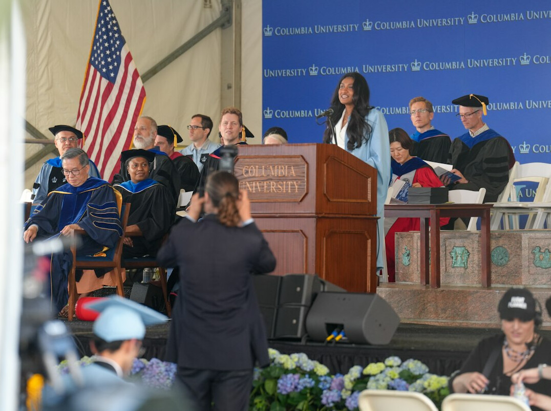 Moderator speaking at a podium during a public discussion